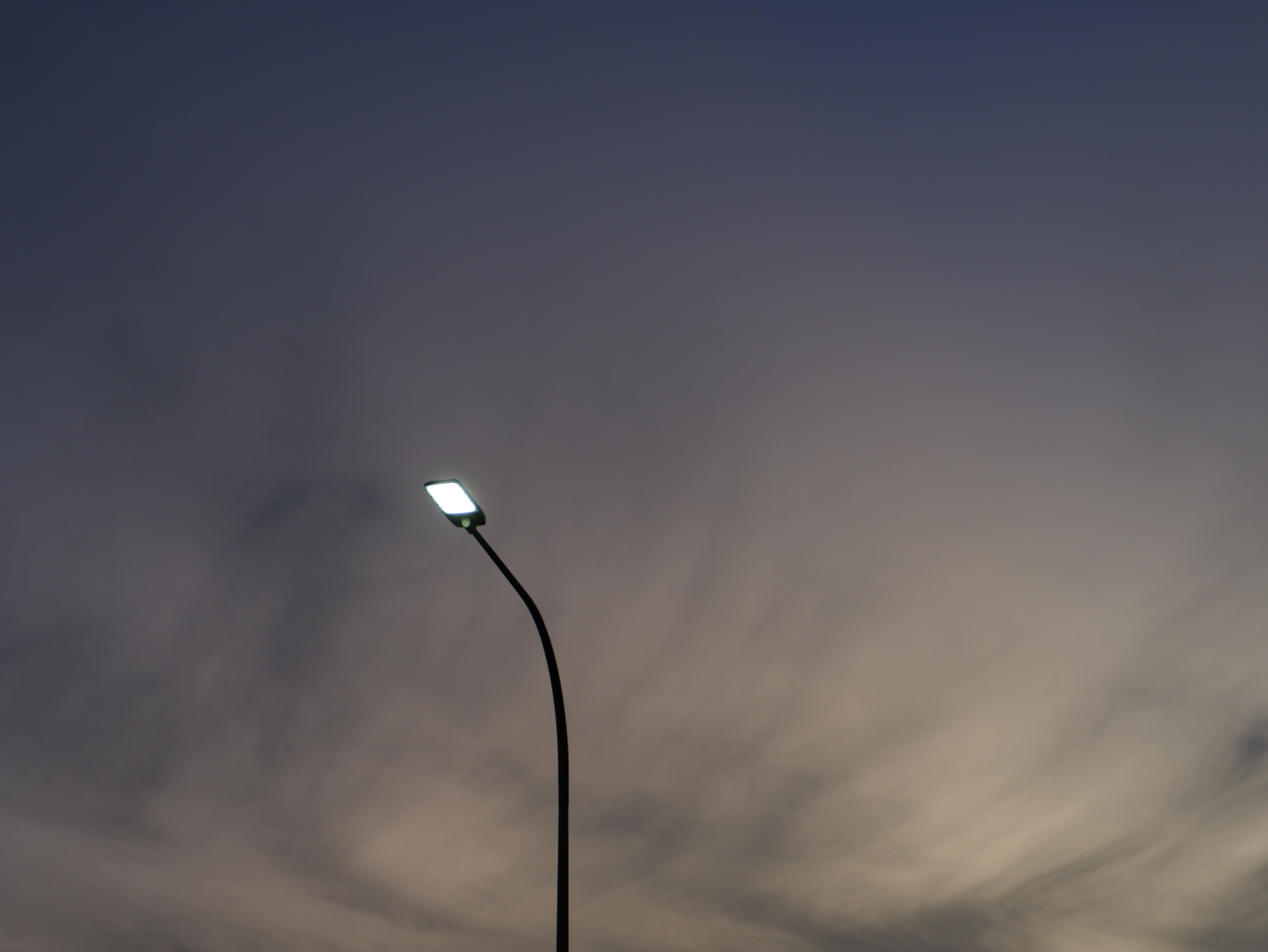 The lamps were still shining, and the wispy clouds were casting shadows in the sky.