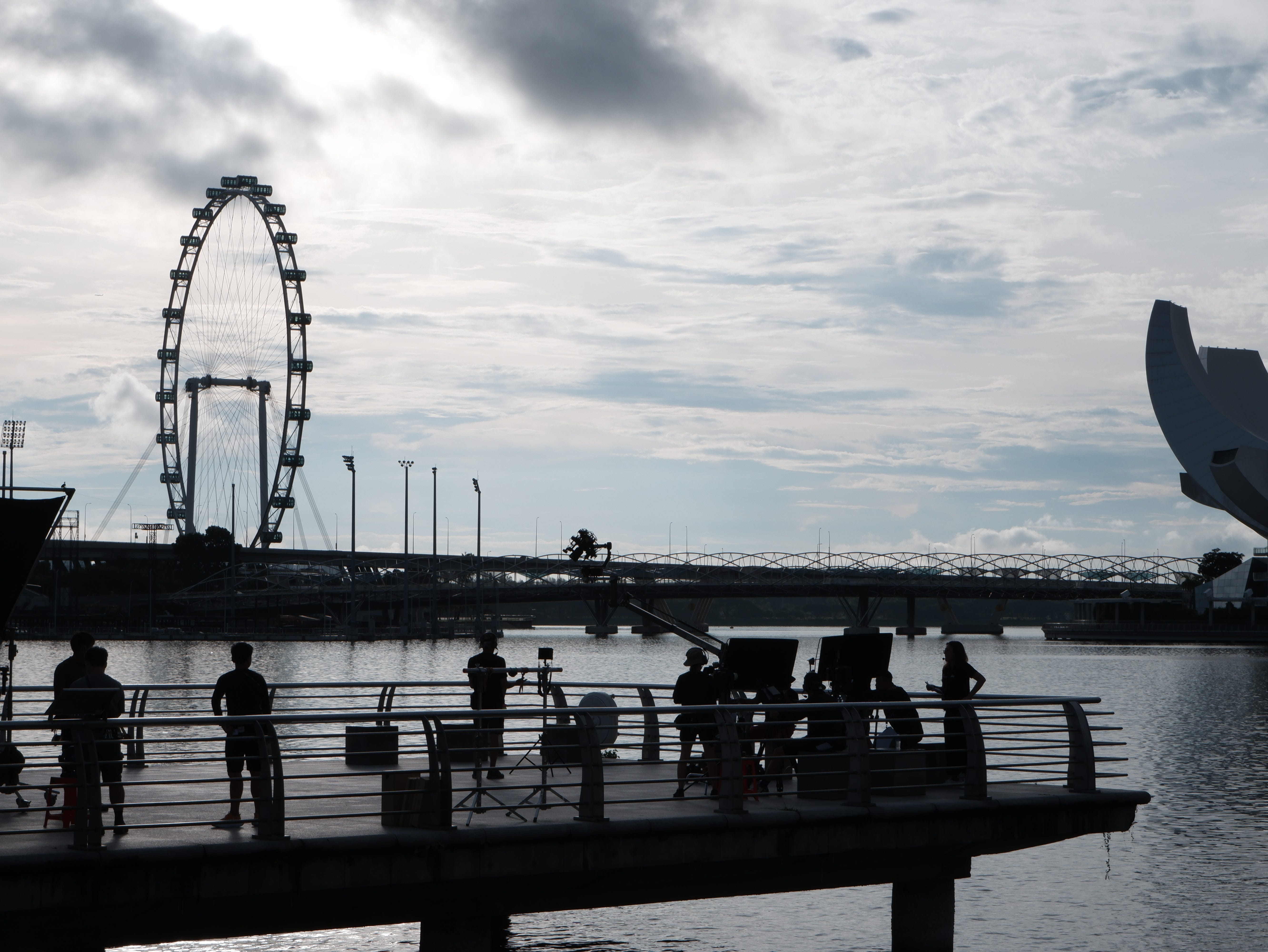 A camera crew at work against the rising sun in Merlion Park.