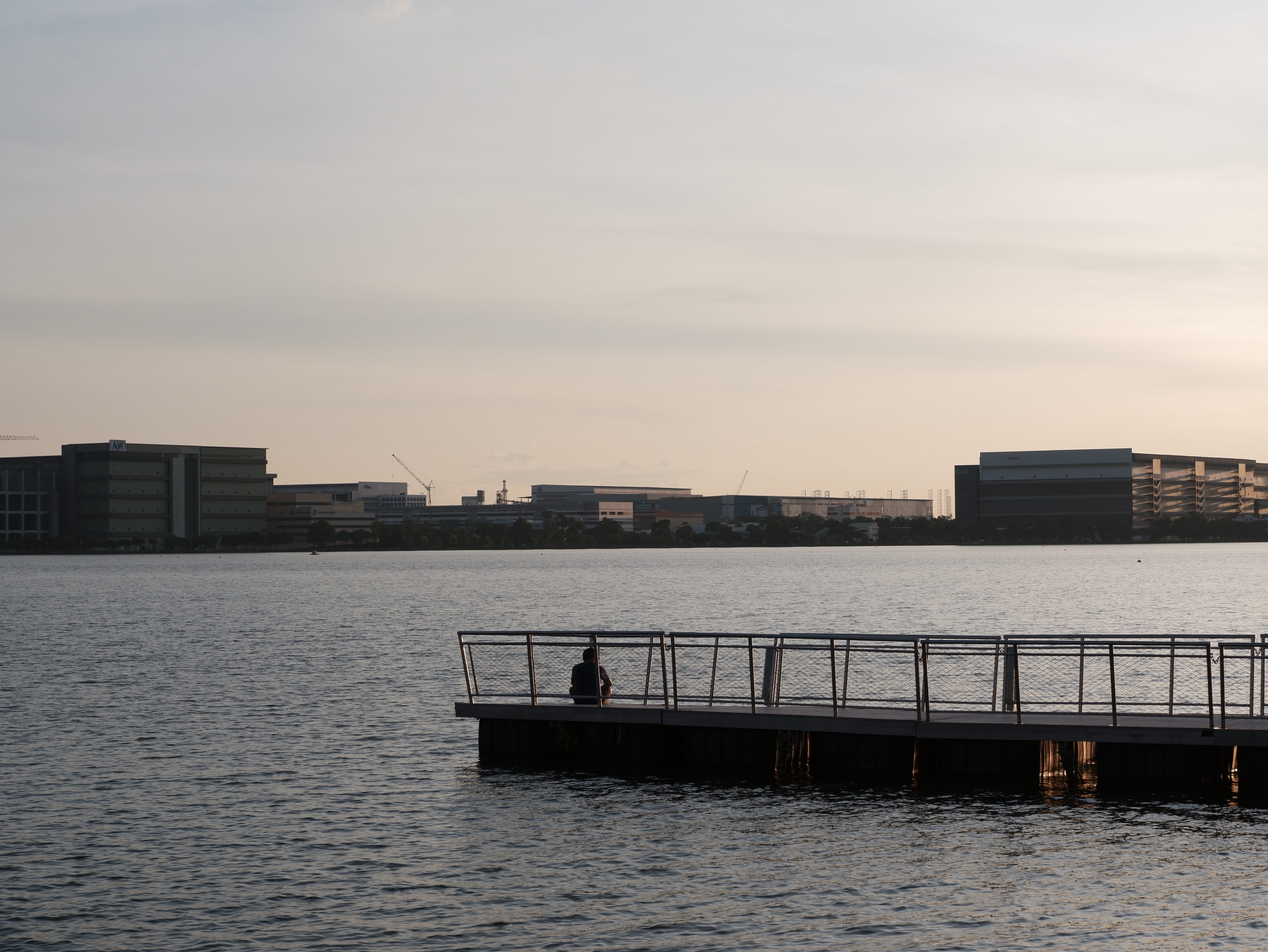 A man sits on the floating pier, admiring the sunset.