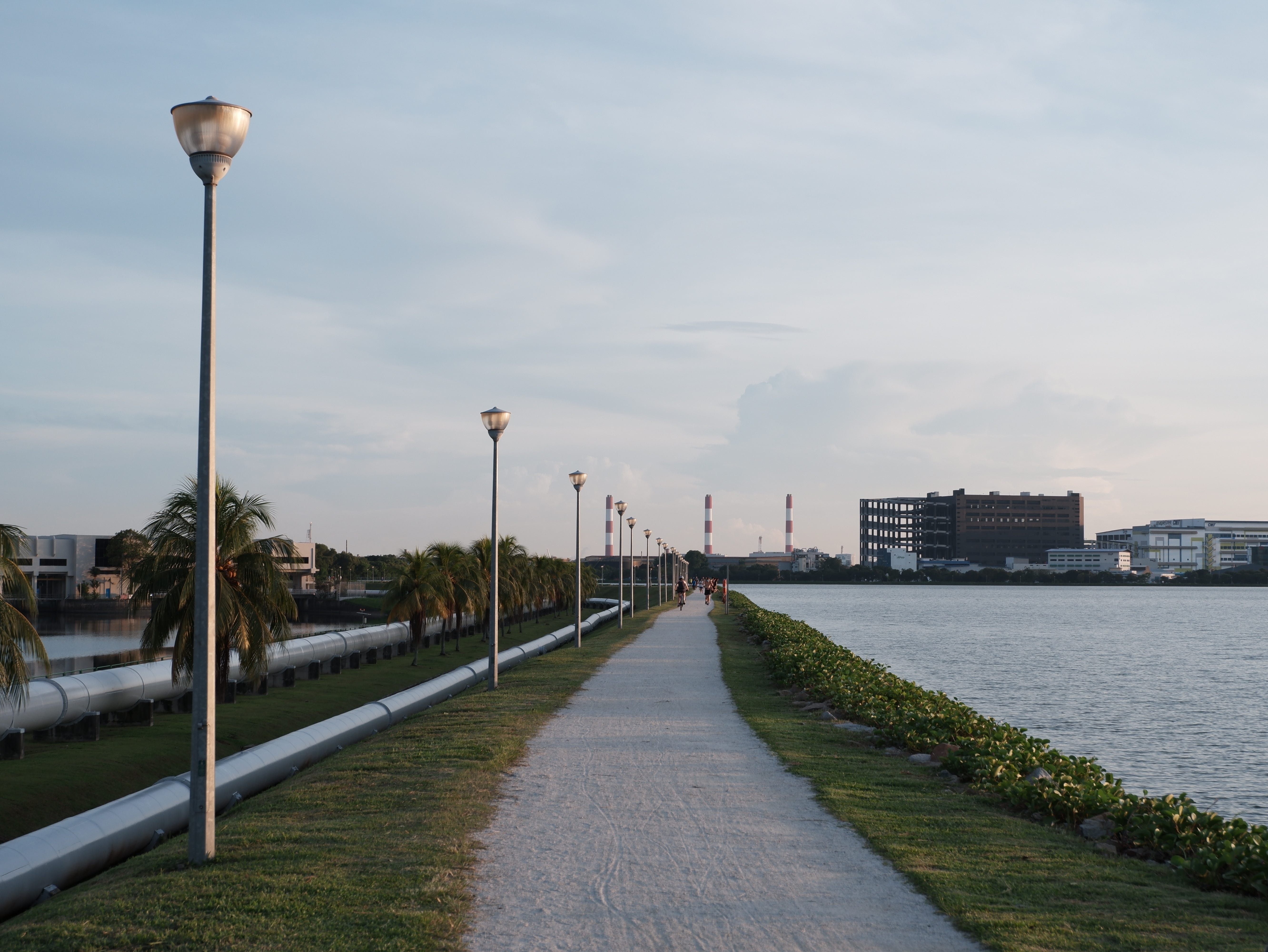 The eastern bank walkway stretches into the horizon. Joggers and cyclists are seen in the distance.
