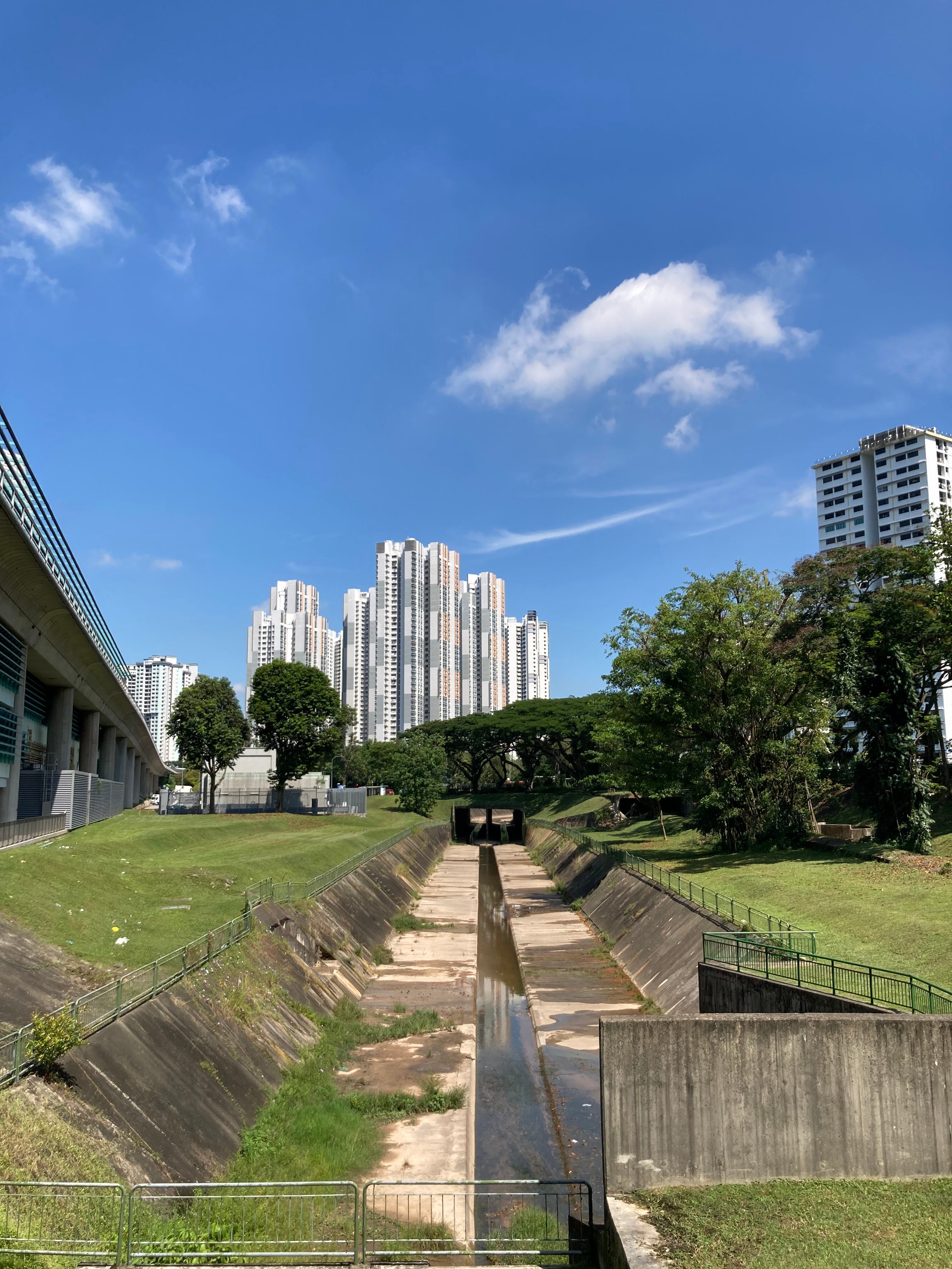 The start of the canal, visible just as you exit the Buona Vista MRT station on a bright, sunny day. Green barricades block access to the canal.