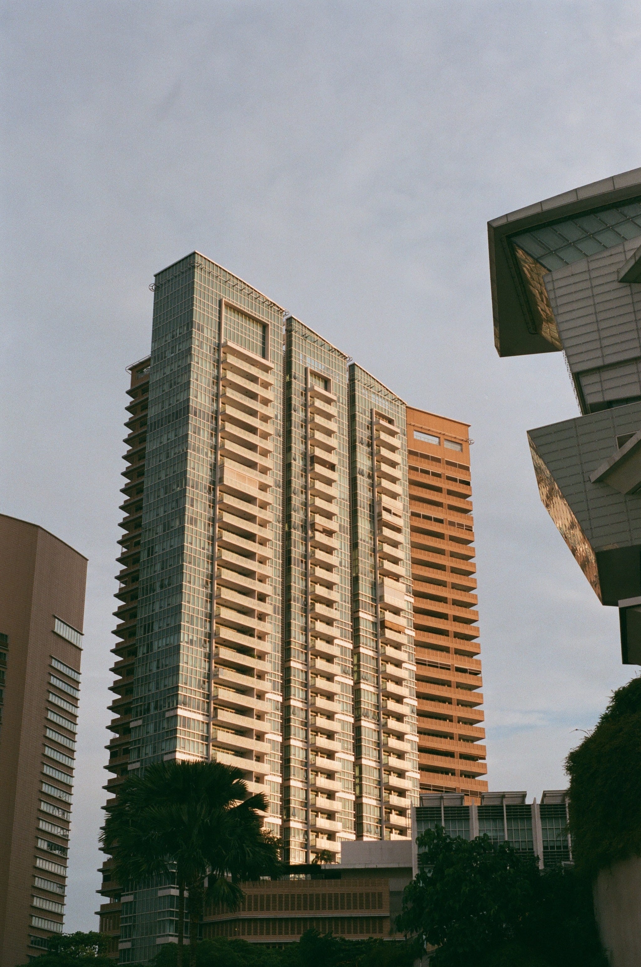 The canal emerges from a dark tunnel underneath the Buona Vista MRT station. Behind the MRT station, the Metropolis tower and the Ministry of Education office buildings catch the light from the sunset.